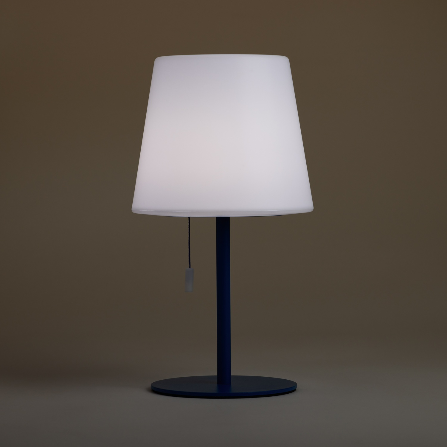 Una lampada bianca con base blu su una superficie grigia.