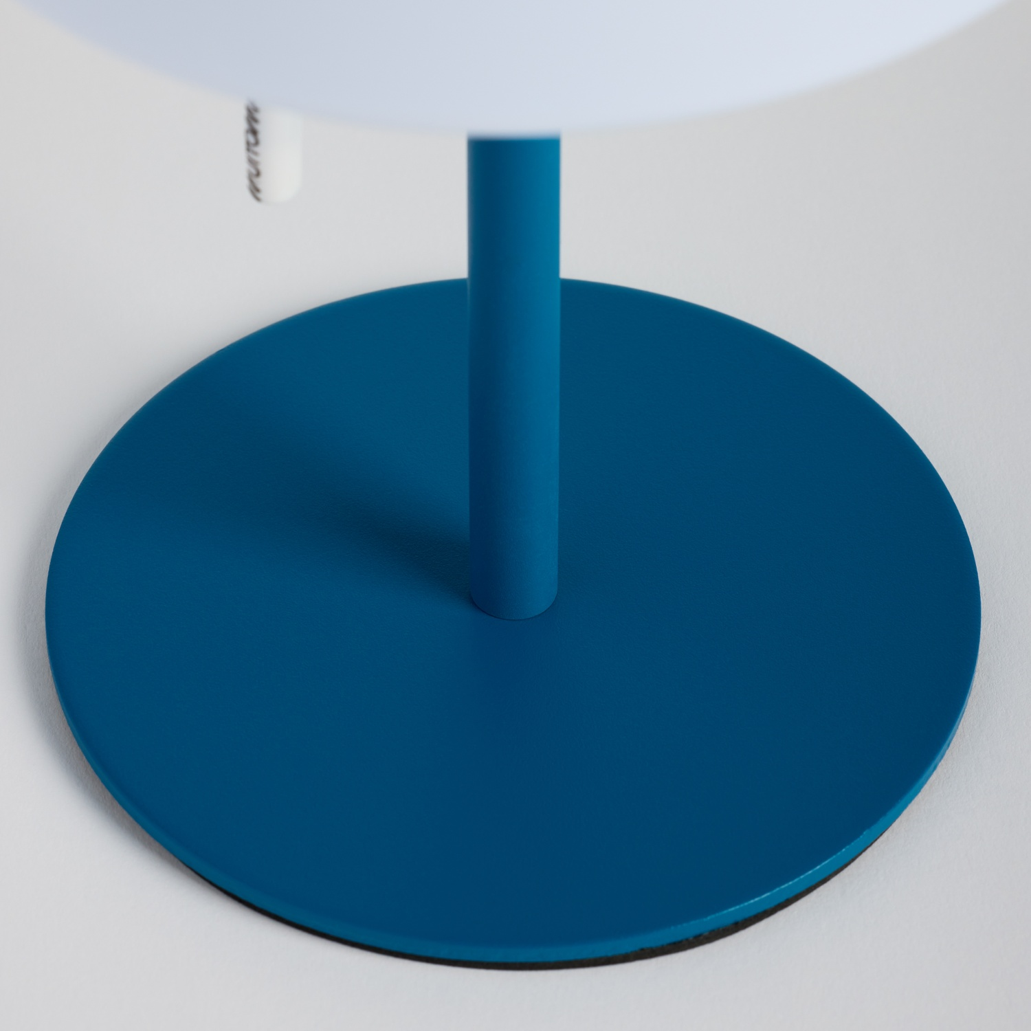 Una base di lampada rotonda blu con un supporto verticale su sfondo bianco.