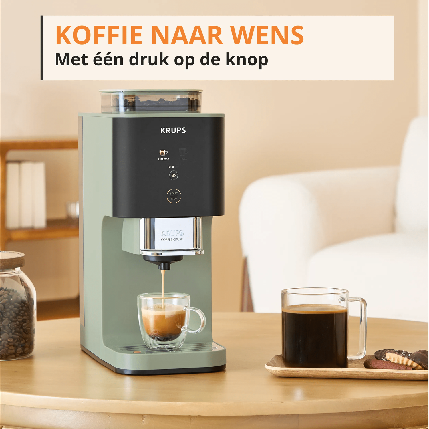 Een groene Krups koffiemachine zet espresso in een glazen kop. Daarnaast een mok koffie en koekjes.