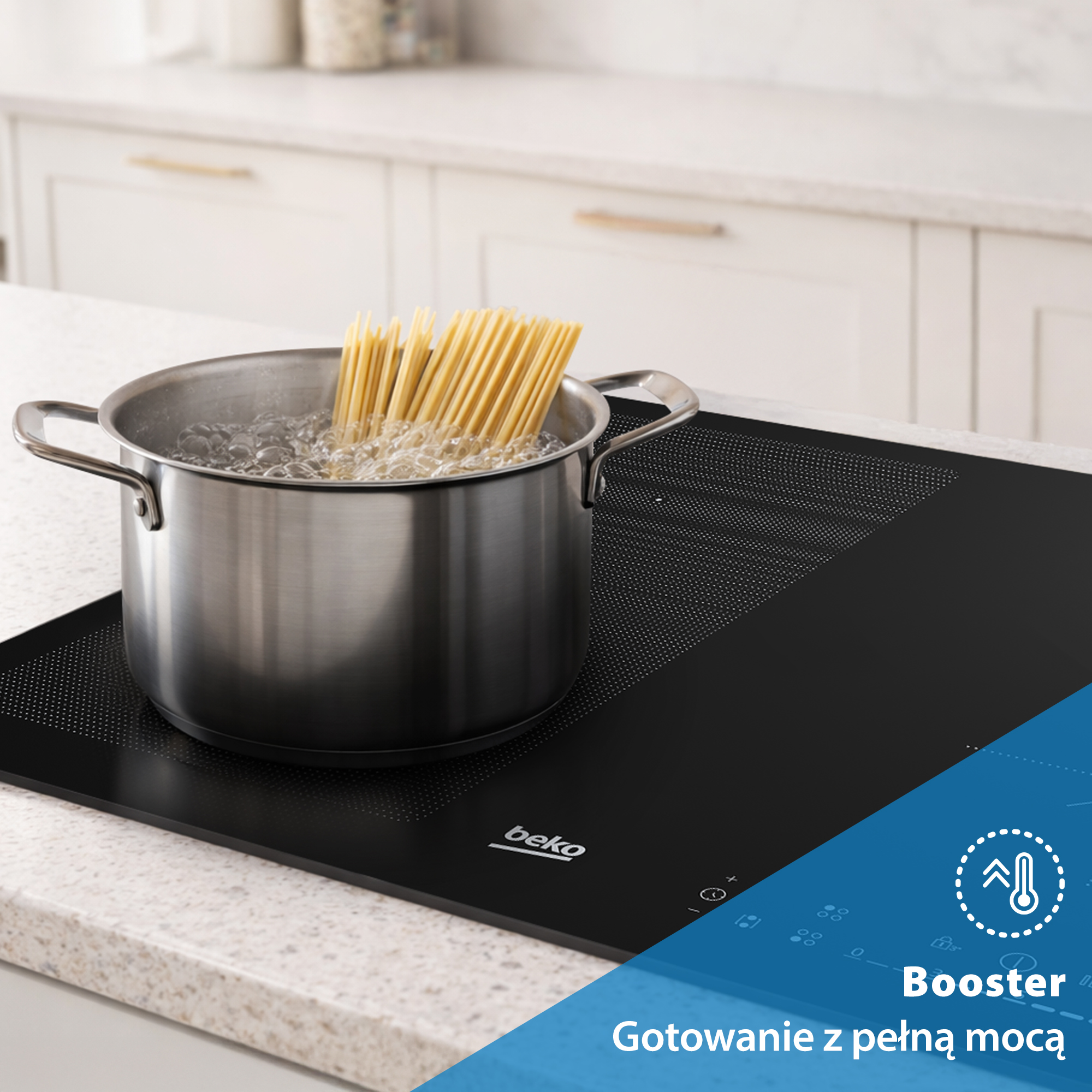 Garnek spaghetti gotuje się w wodzie na czarnej płycie indukcyjnej z białym blatem.