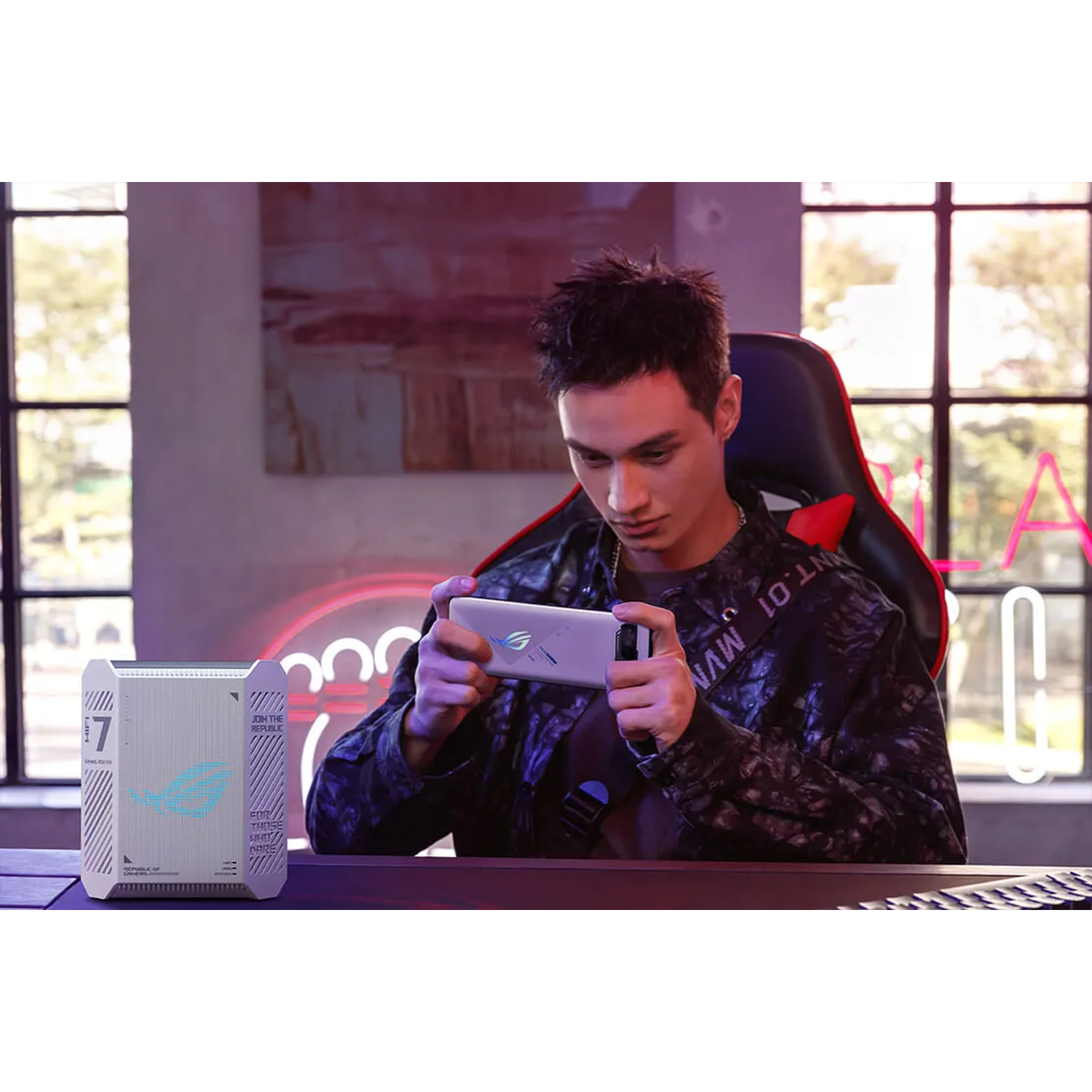 A man plays on his phone, next to a white gaming router.