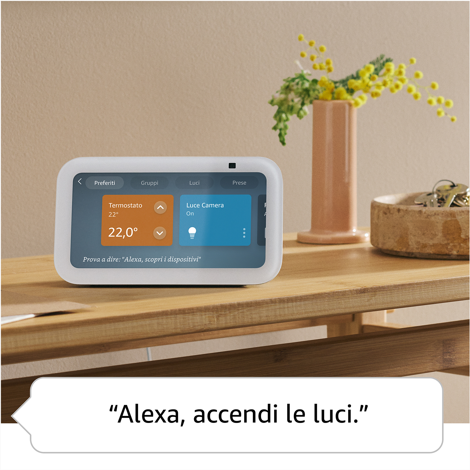 Un display intelligente mostra i controlli di termostato e luci. Un vaso con fiori gialli è vicino.