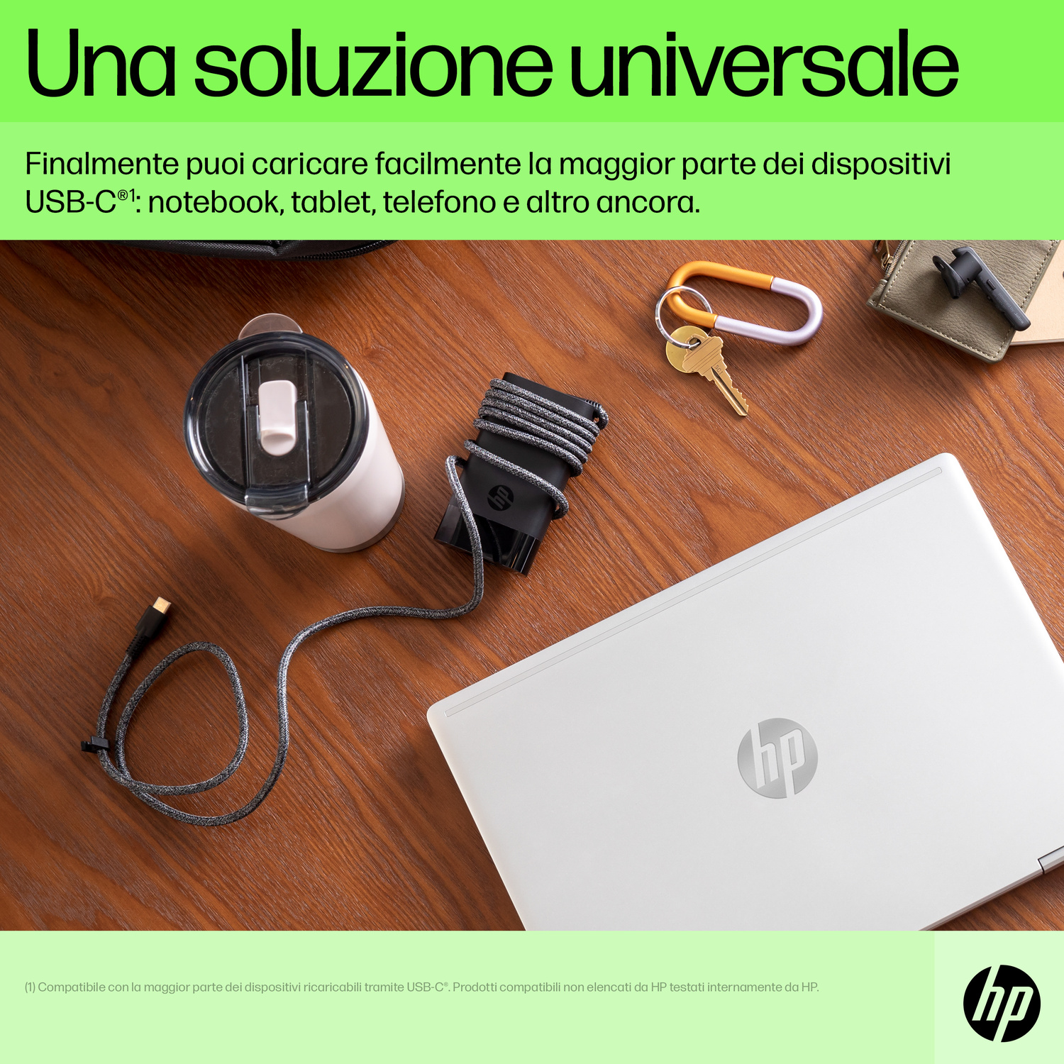 Un laptop, tazza, portachiavi e cavo USB-C su un tavolo di legno.