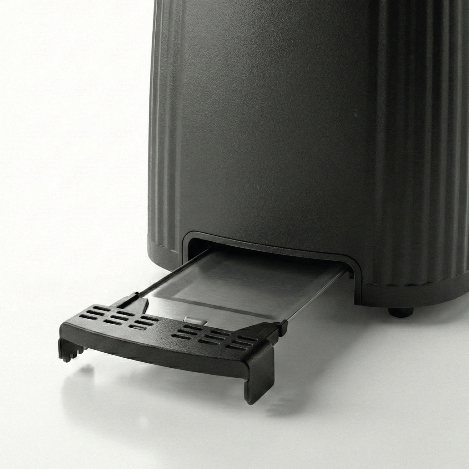 Close-up of a black bread slicer with its crumb tray extended.