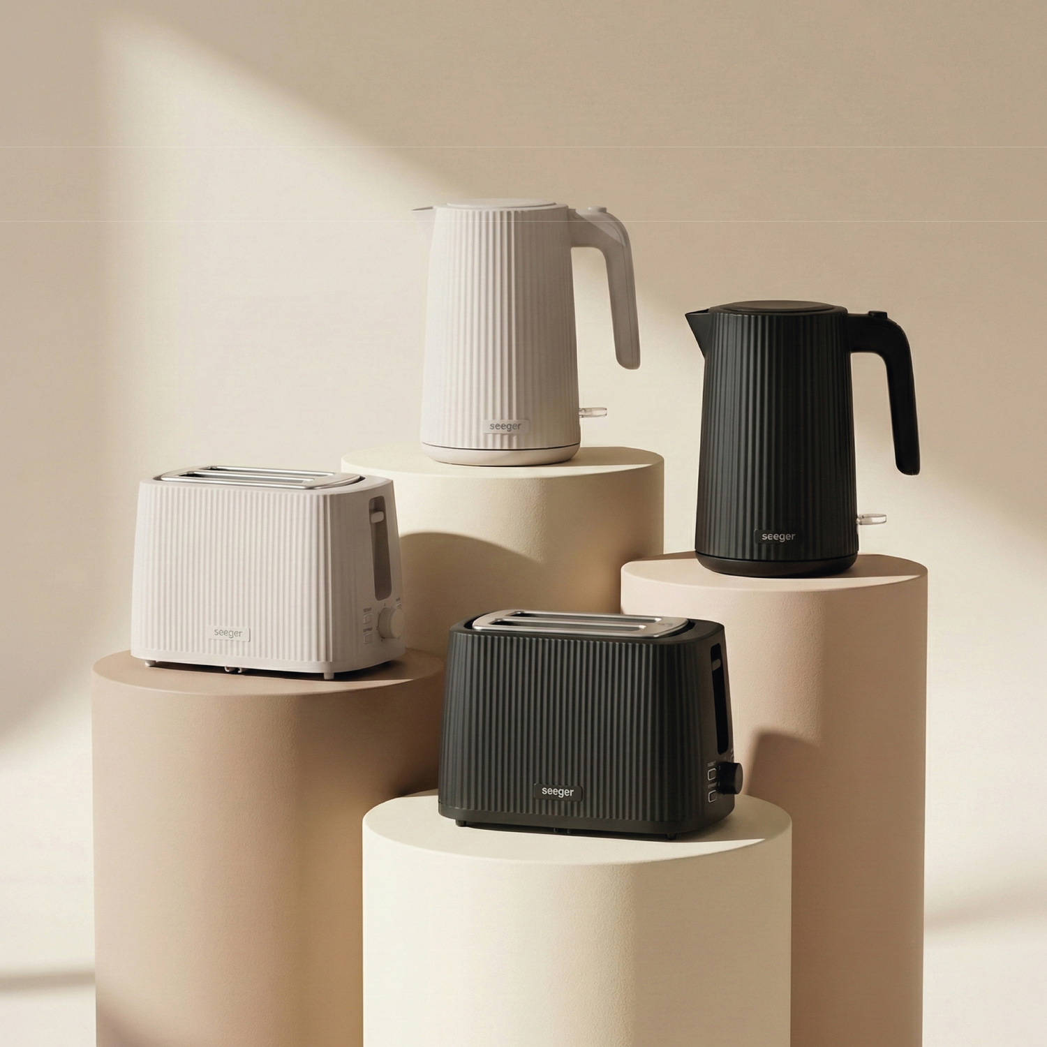 Two white and two black toasters and kettles displayed on pedestals.