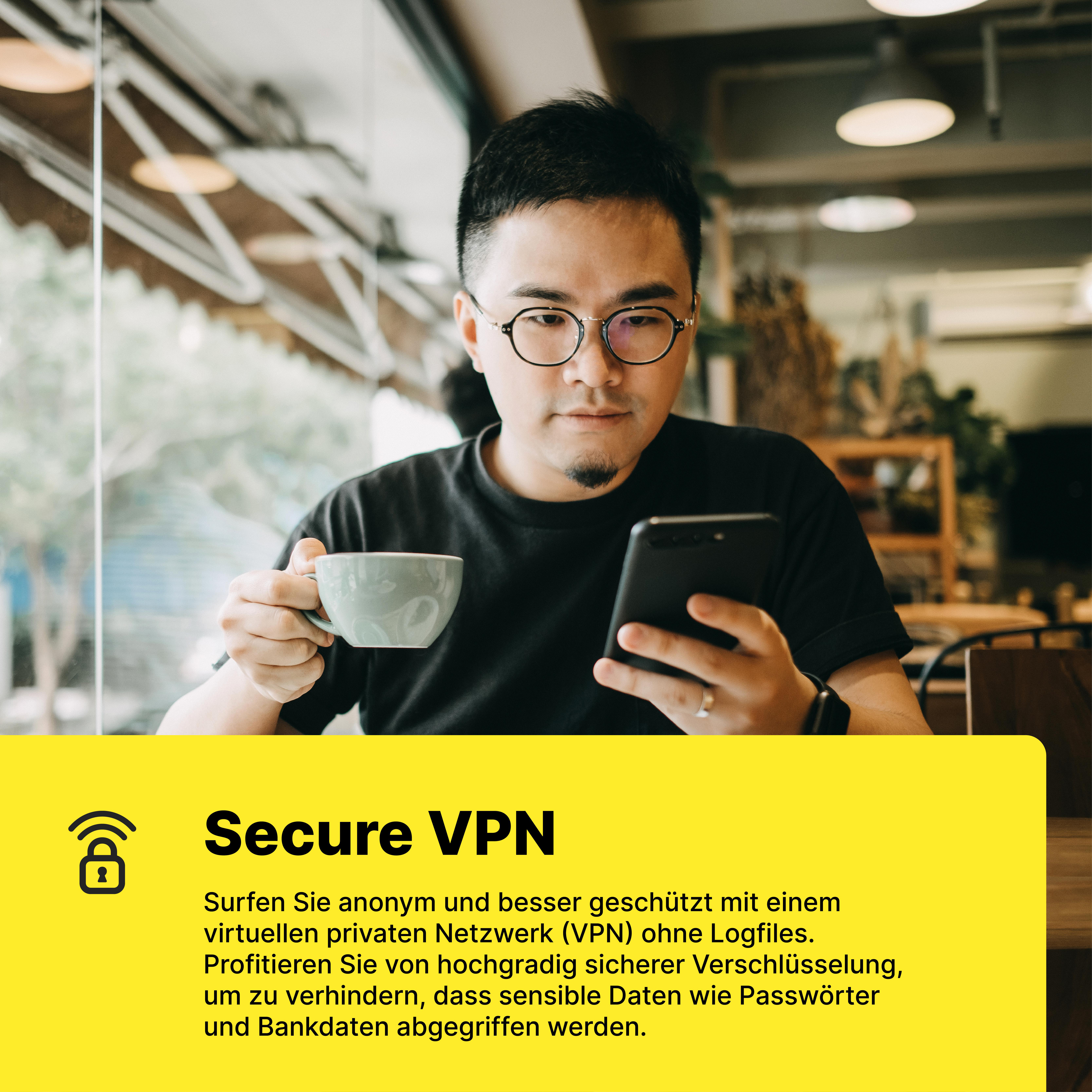 Mann mit Brille hält Tasse und Handy in einem Café.