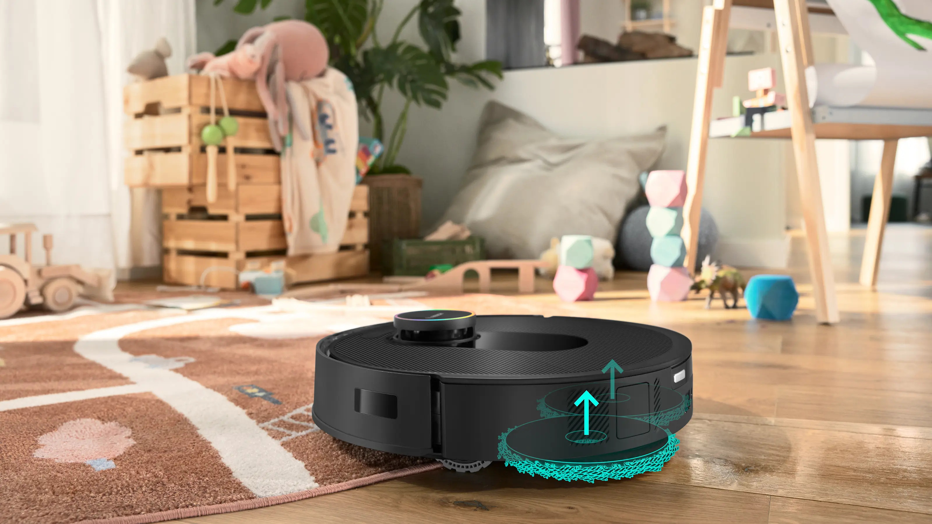 Czarny robot odkurzający czyści dywan z zabawkami dla dzieci w tle.