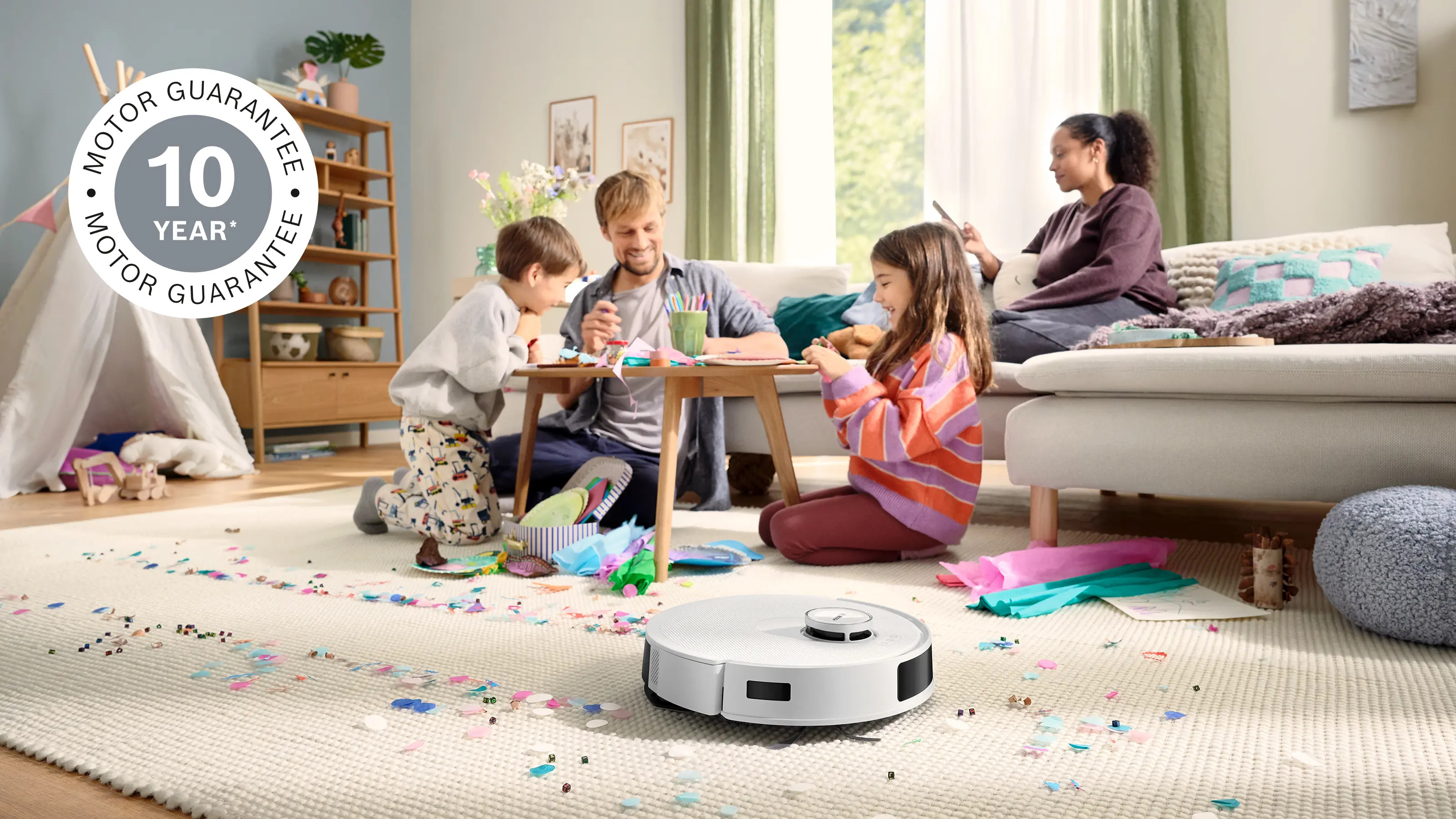 Robot sprzątający czyści pokój z konfetti, podczas gdy rodzina się bawi.