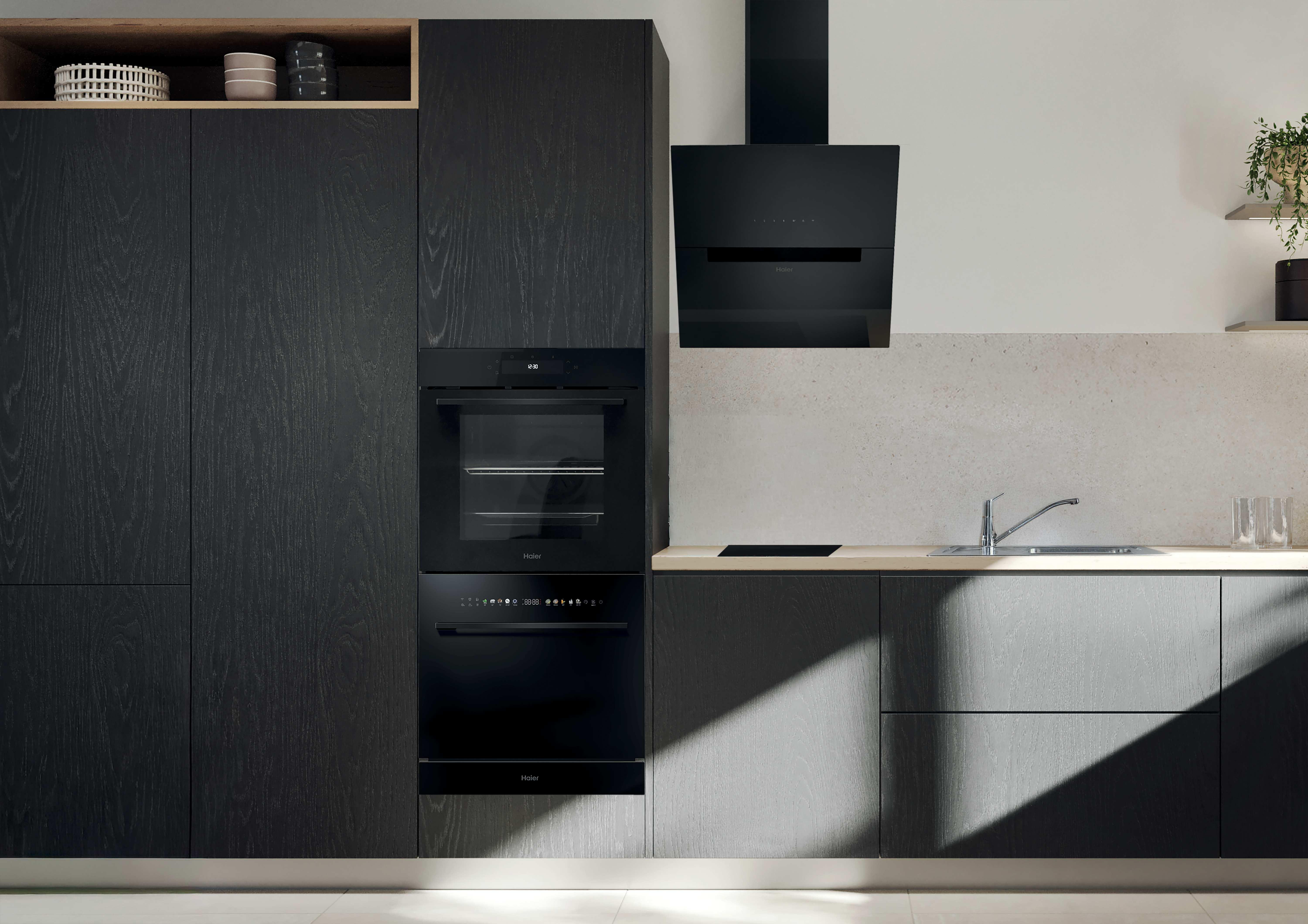 Moderne schwarze Küche mit Holzmaserung, Backofen, Spüle und Dunstabzugshaube.