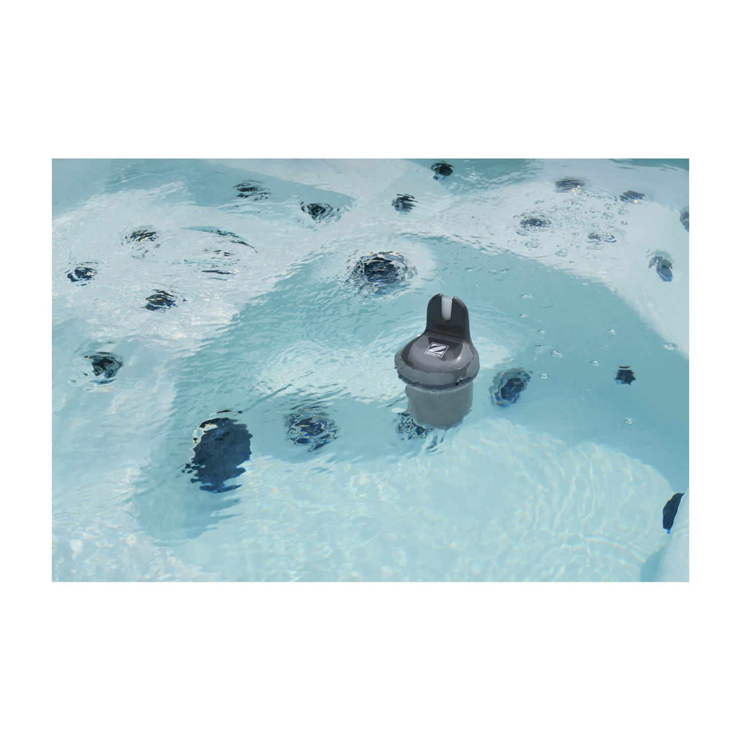 Un misuratore di qualità dell'acqua grigio galleggia in una vasca idromassaggio blu chiaro.