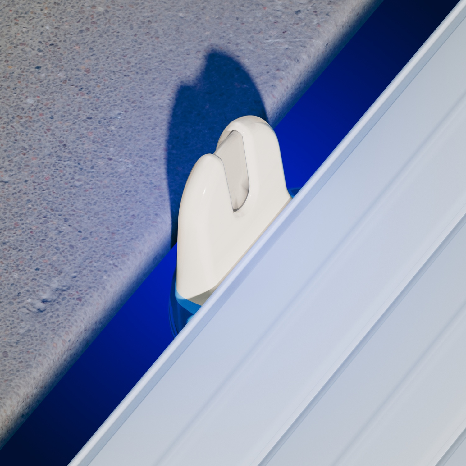 Un gancio bianco si estende in un canale blu, accanto a un muro grigio.