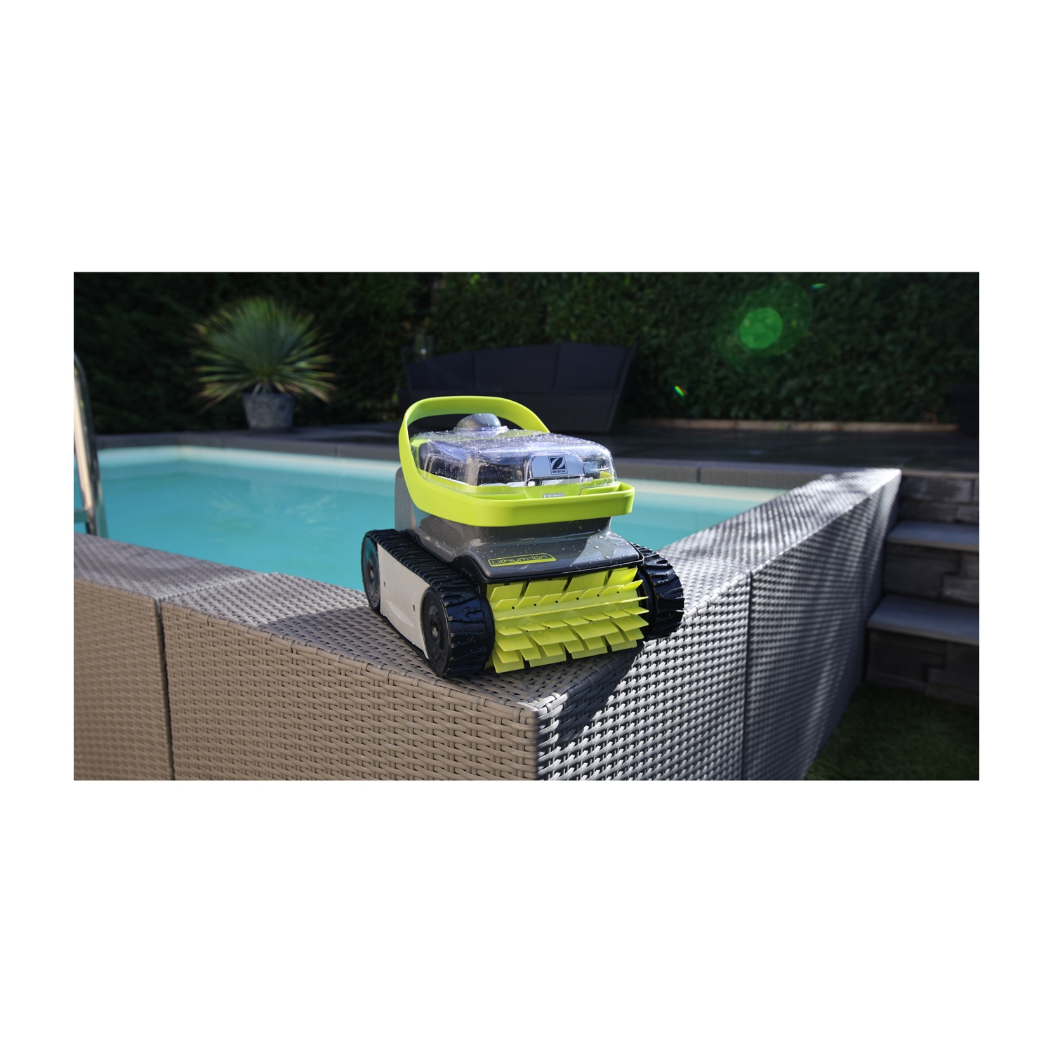 Un robot per piscina verde con ruote è seduto su un bordo intrecciato accanto a una piscina.