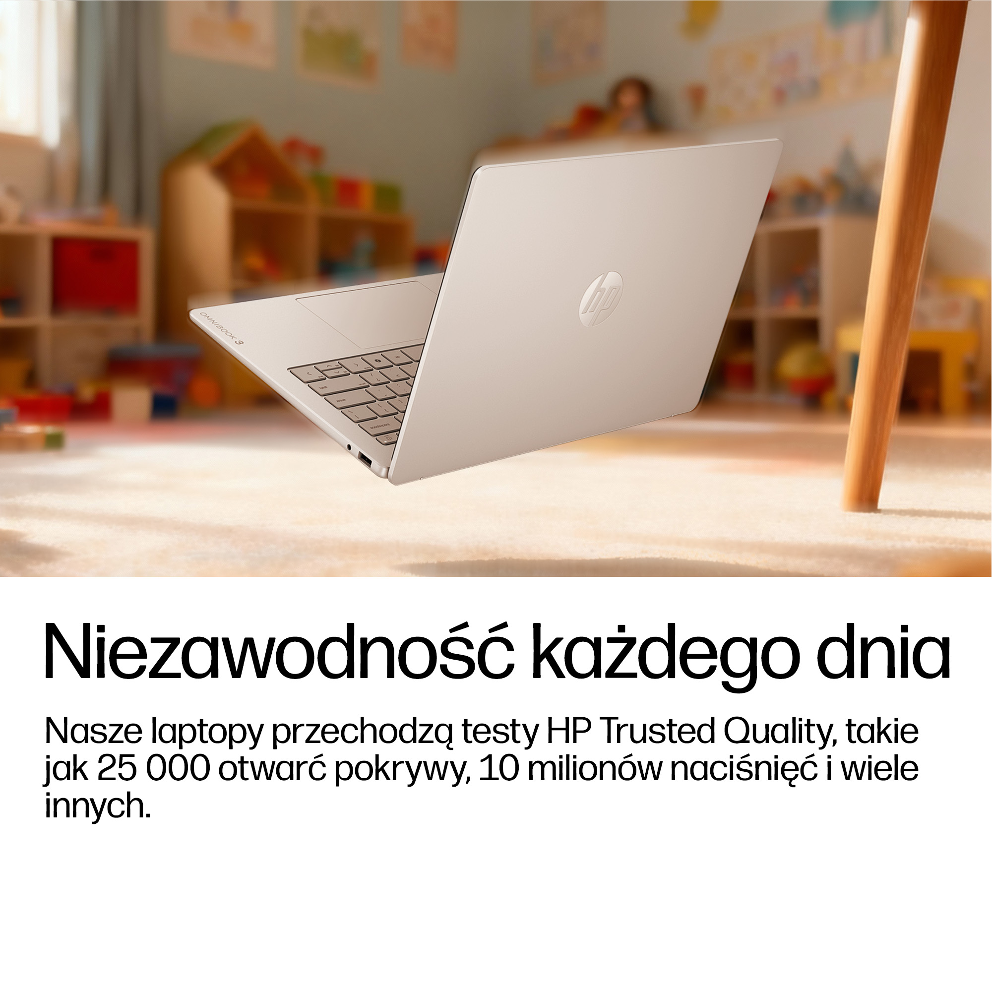 Srebrny laptop HP z klawiaturą na tle nieostrego pokoju dziecięcego.