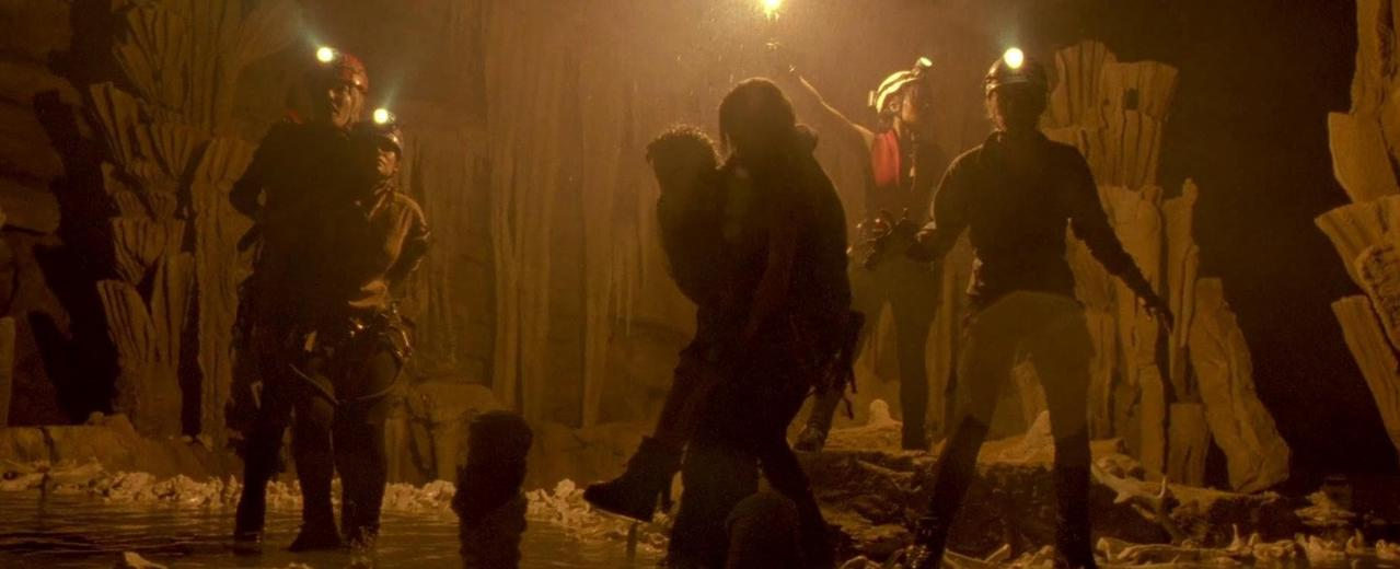 Eine Gruppe von Höhlenforschern mit Stirnlampen in einer Höhle mit Wasser.