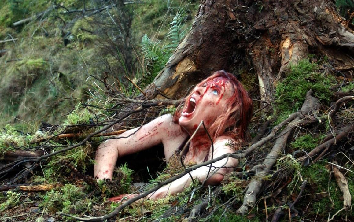 Verletzte Frau mit blutigen Wunden, die in einem Wald liegt.