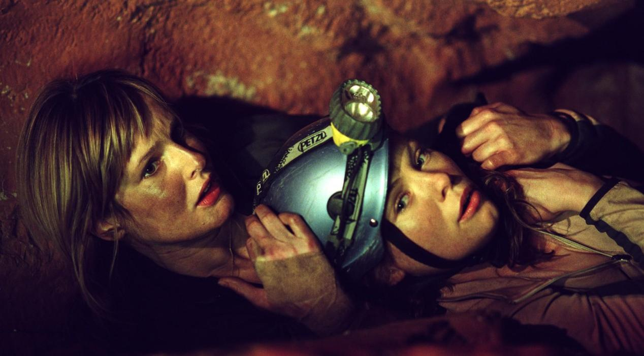 Zwei Frauen liegen in einer Höhle, eine trägt einen Helm mit Lampe.