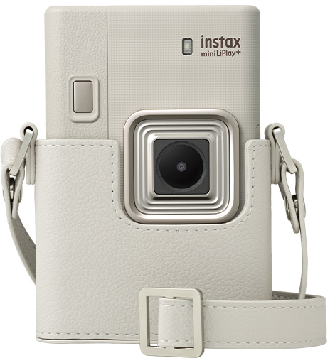 Egy fehér Instax mini LiPlay+ kamera egy hozzáillő fehér bőrtokban, pánttal.