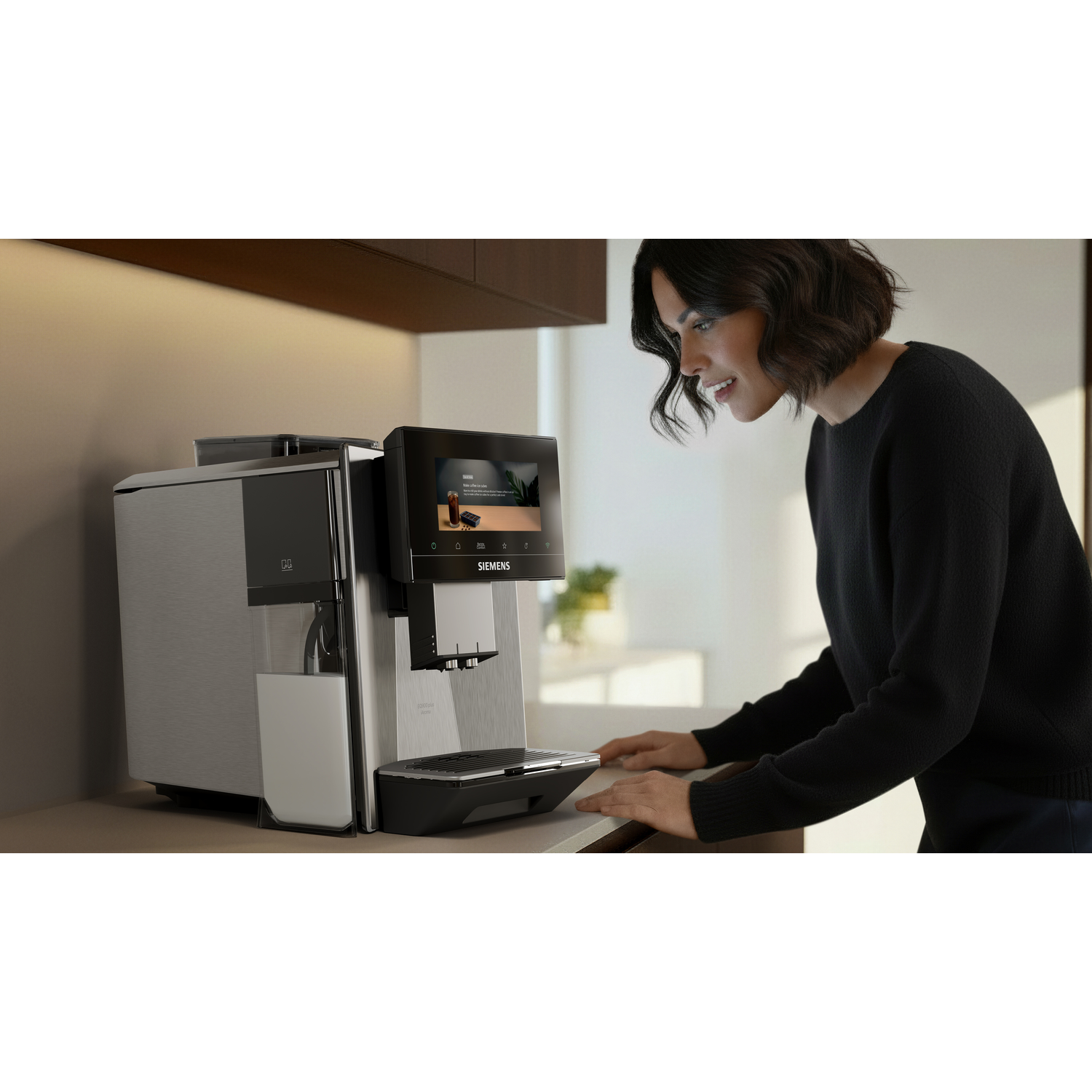 Femme devant une machine à café avec réservoir à lait et écran tactile.