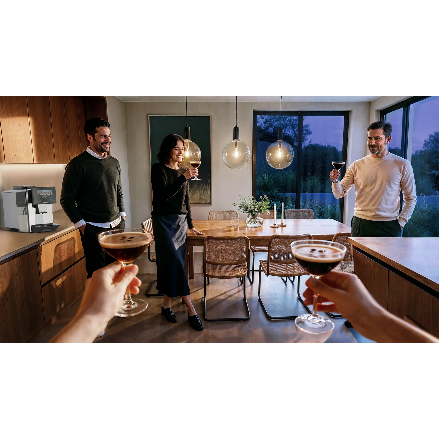 Quatre personnes trinquent avec des cocktails dans une maison moderne.