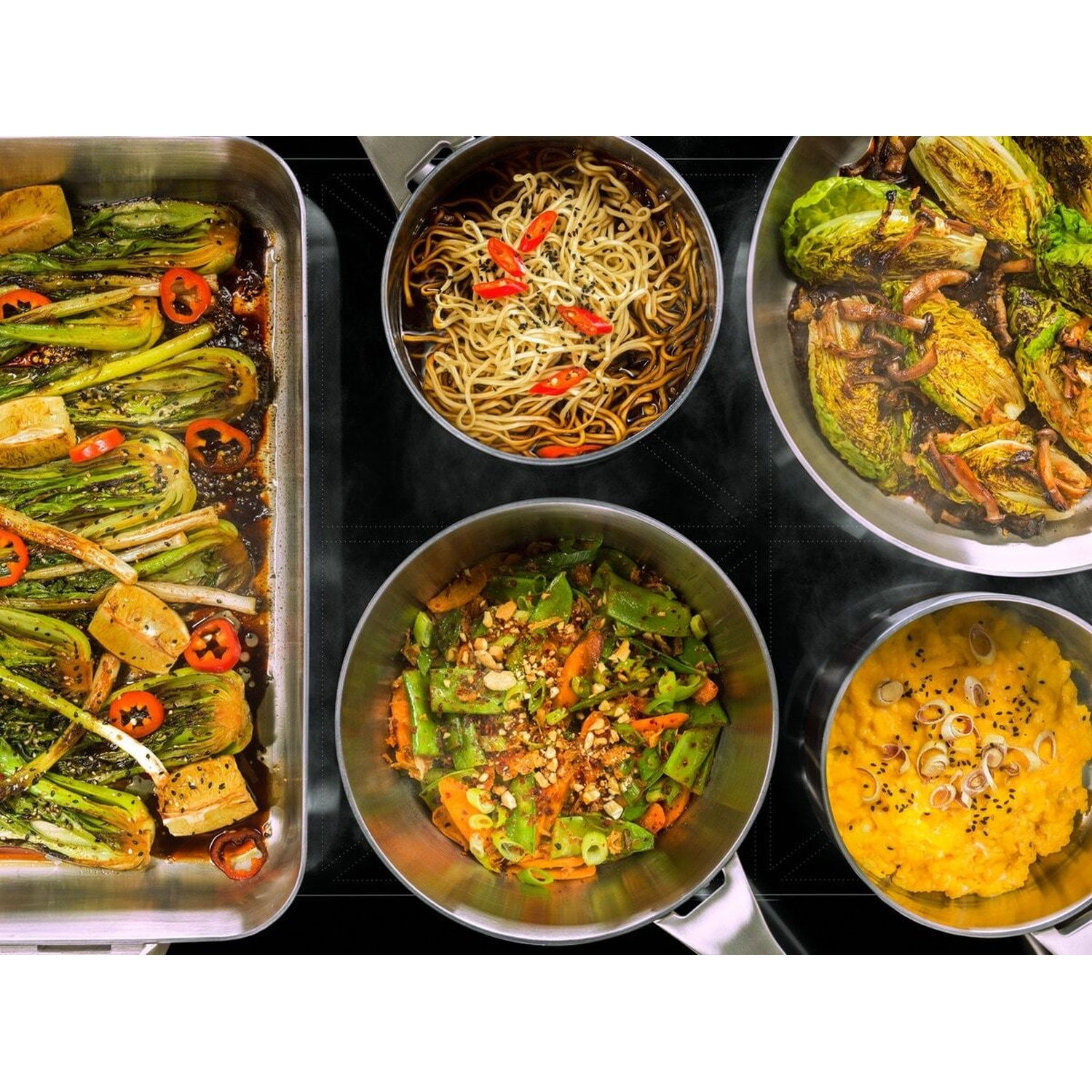 Verdure al vapore, noodles, verdure arrosto e uova strapazzate su un fornello.
