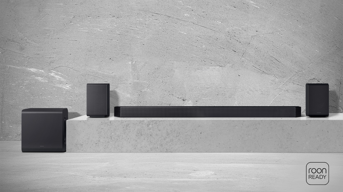 Schwarze Lautsprecher und Soundbar auf Betonpodest vor Betonwand.