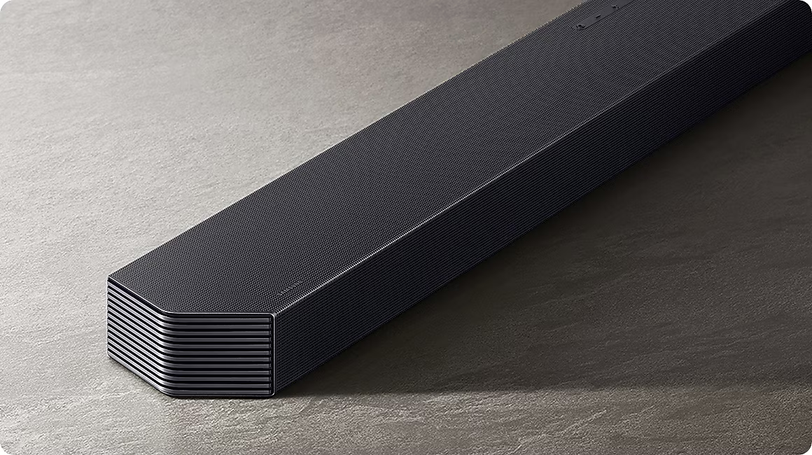 Schwarzer Soundbar auf grauem Steinboden mit dezenter Beleuchtung.