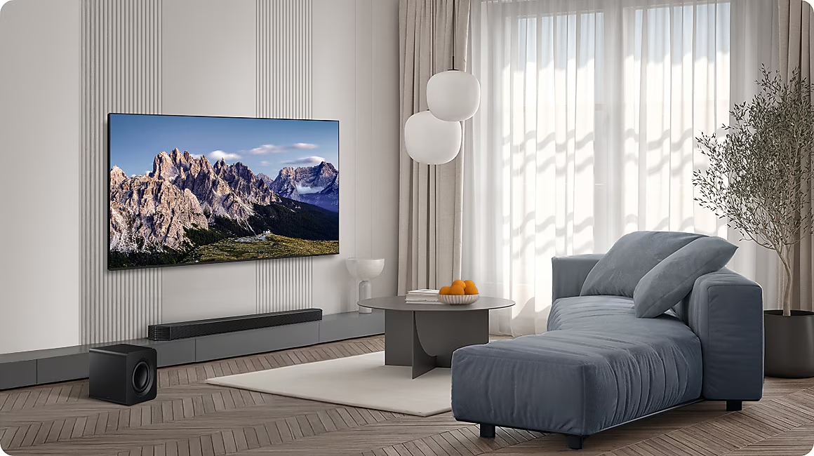 Salon moderne avec une grande TV affichant des montagnes, un canapé gris, une table basse et un caisson.
