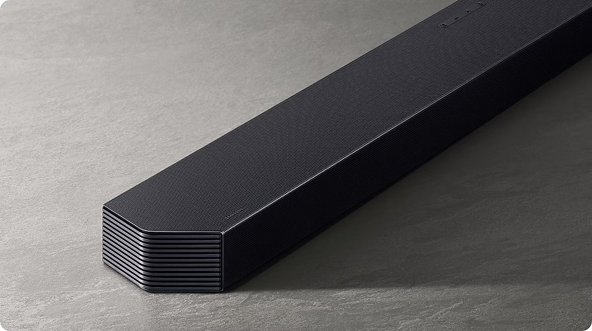 Une barre de son noire avec une grille texturée repose sur une surface grise.