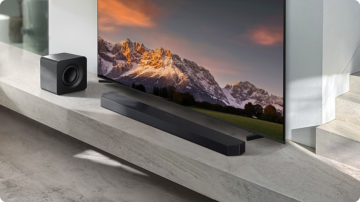 Caisson de basses et barre de son noirs devant un panorama de montagne sur TV.