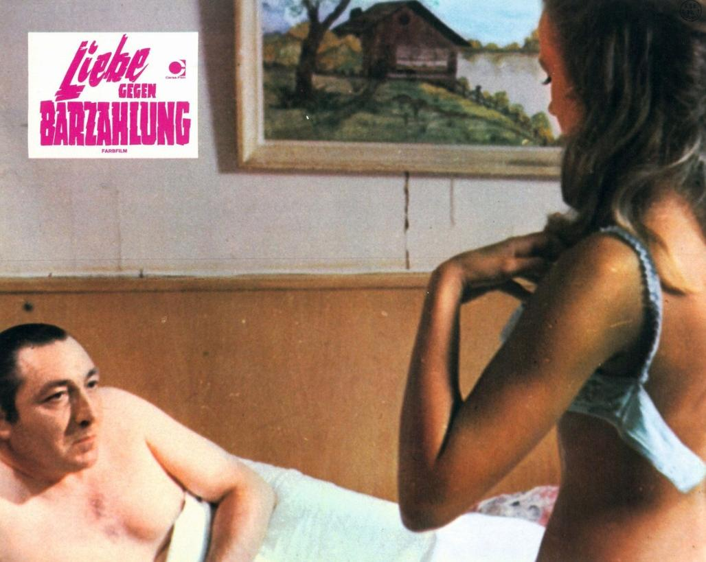 Ein Mann liegt im Bett, eine Frau zieht sich aus. Ein Bild im Hintergrund.