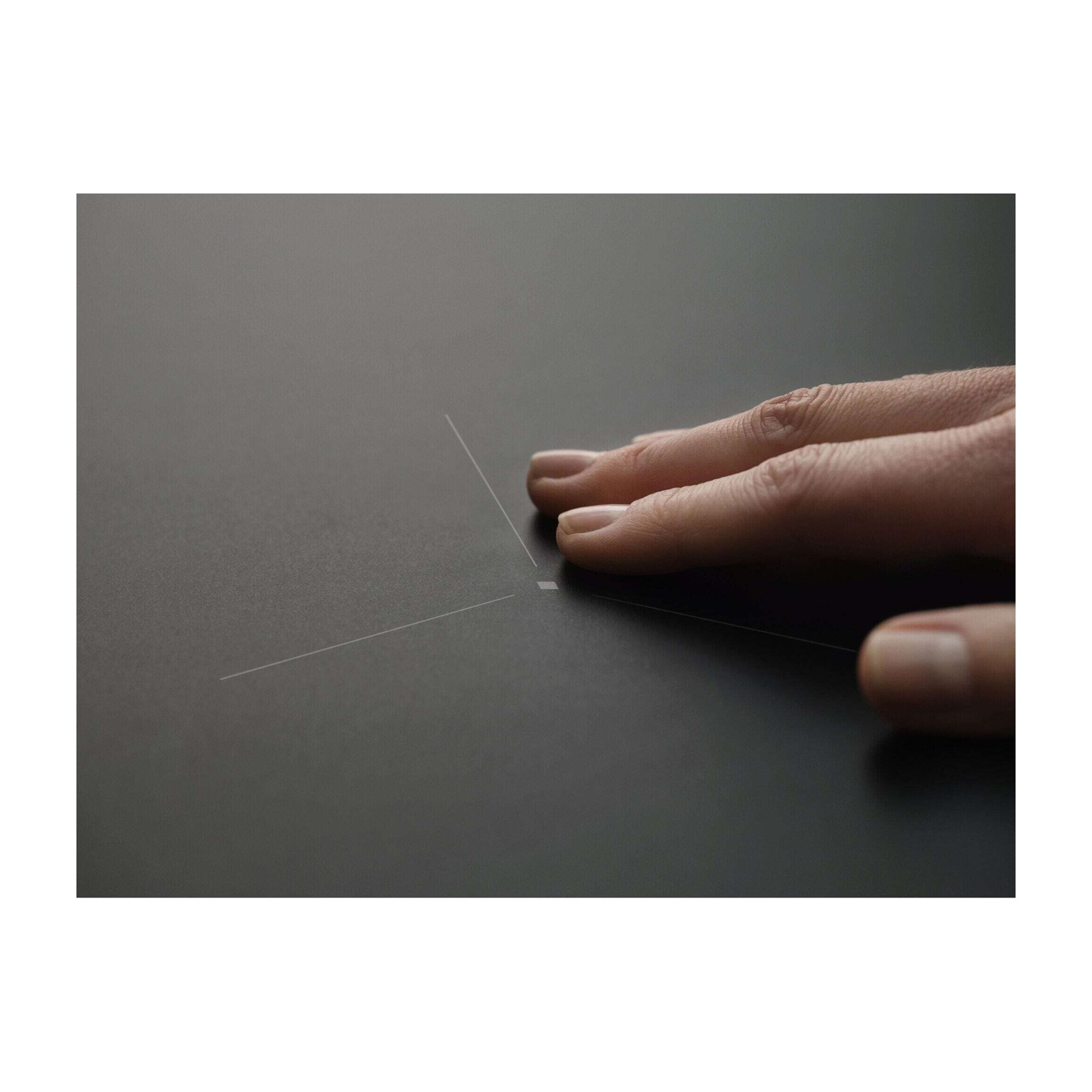 Una mano tocca una superficie scura con linee sottili.