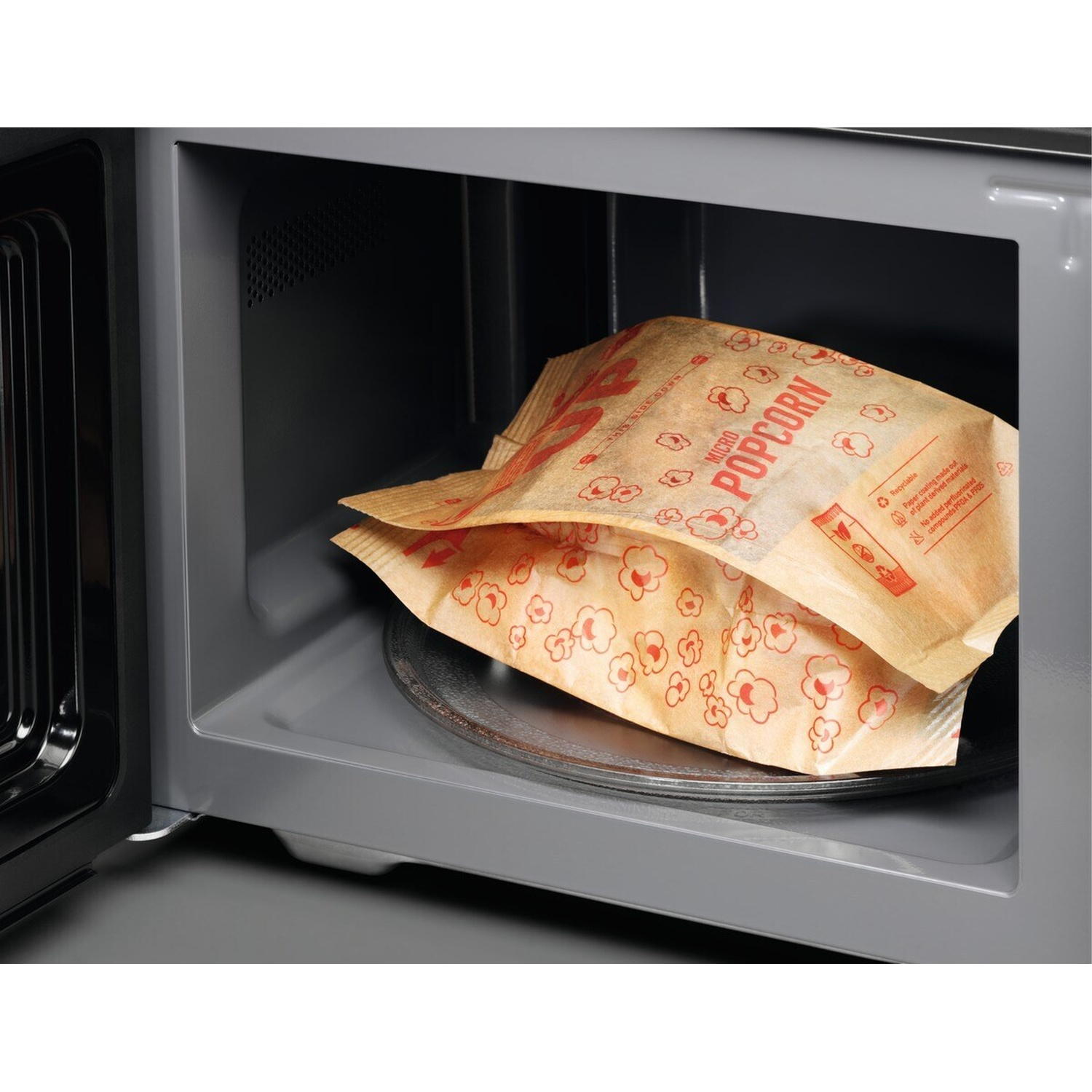 Due sacchetti di popcorn per microonde in un forno a microonde aperto.