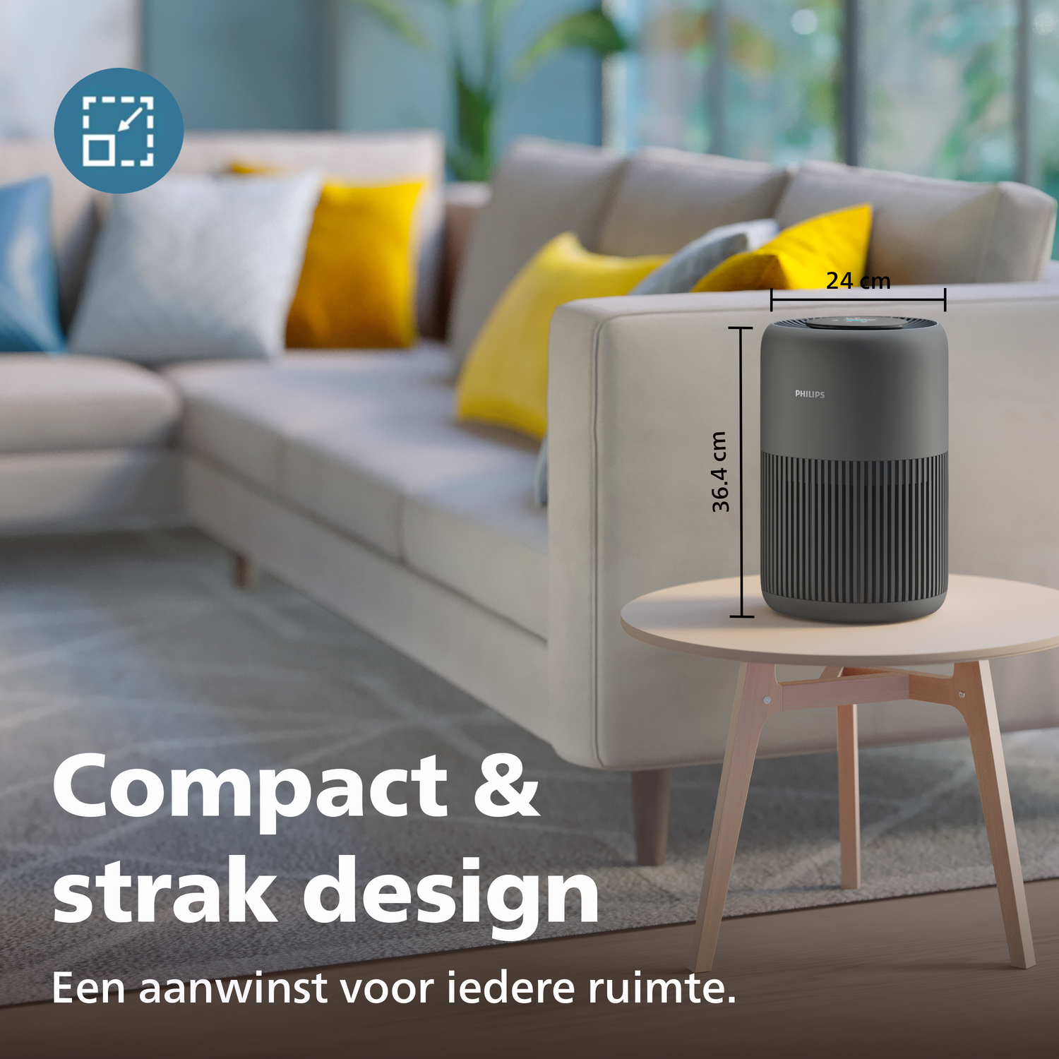 Een compacte, donkere Philips luchtreiniger staat op een tafel naast een bank.