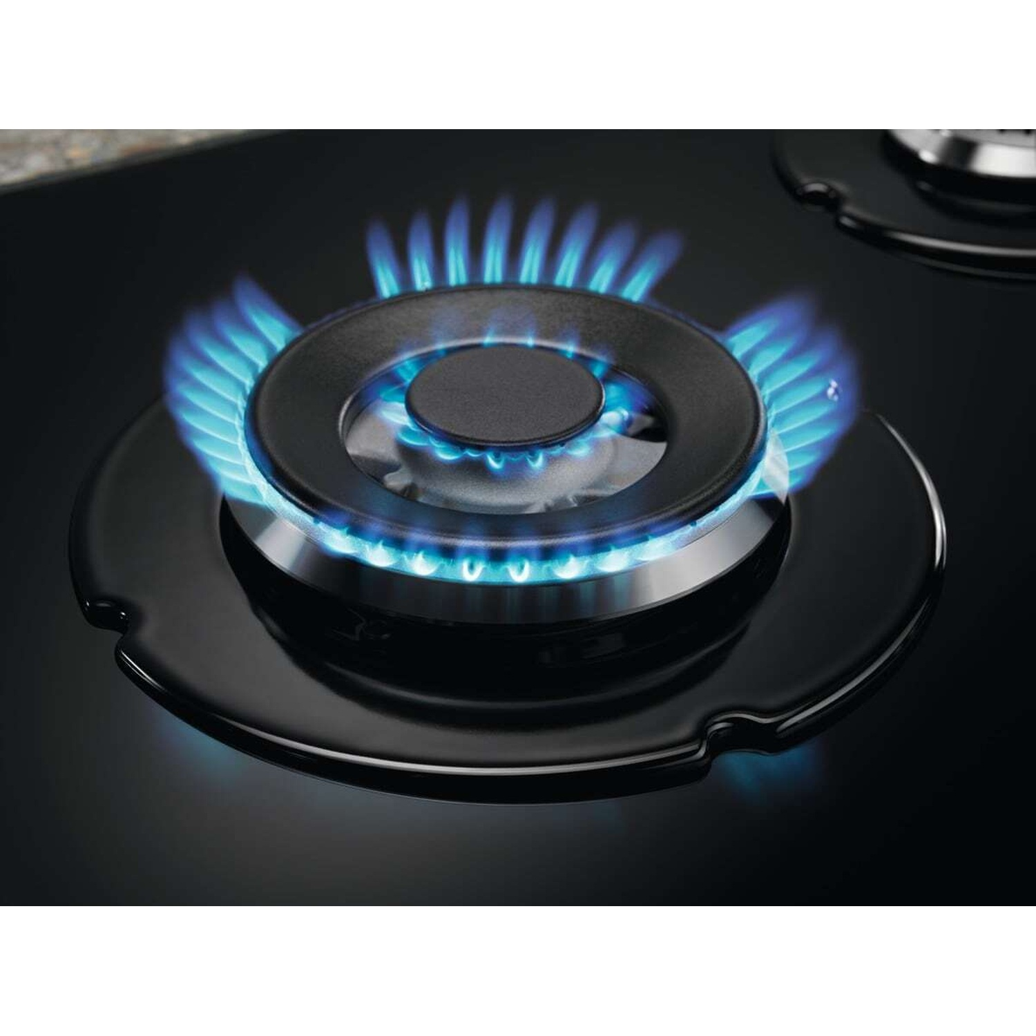 Un bruciatore a gas si accende con fiamme blu su una superficie nera.