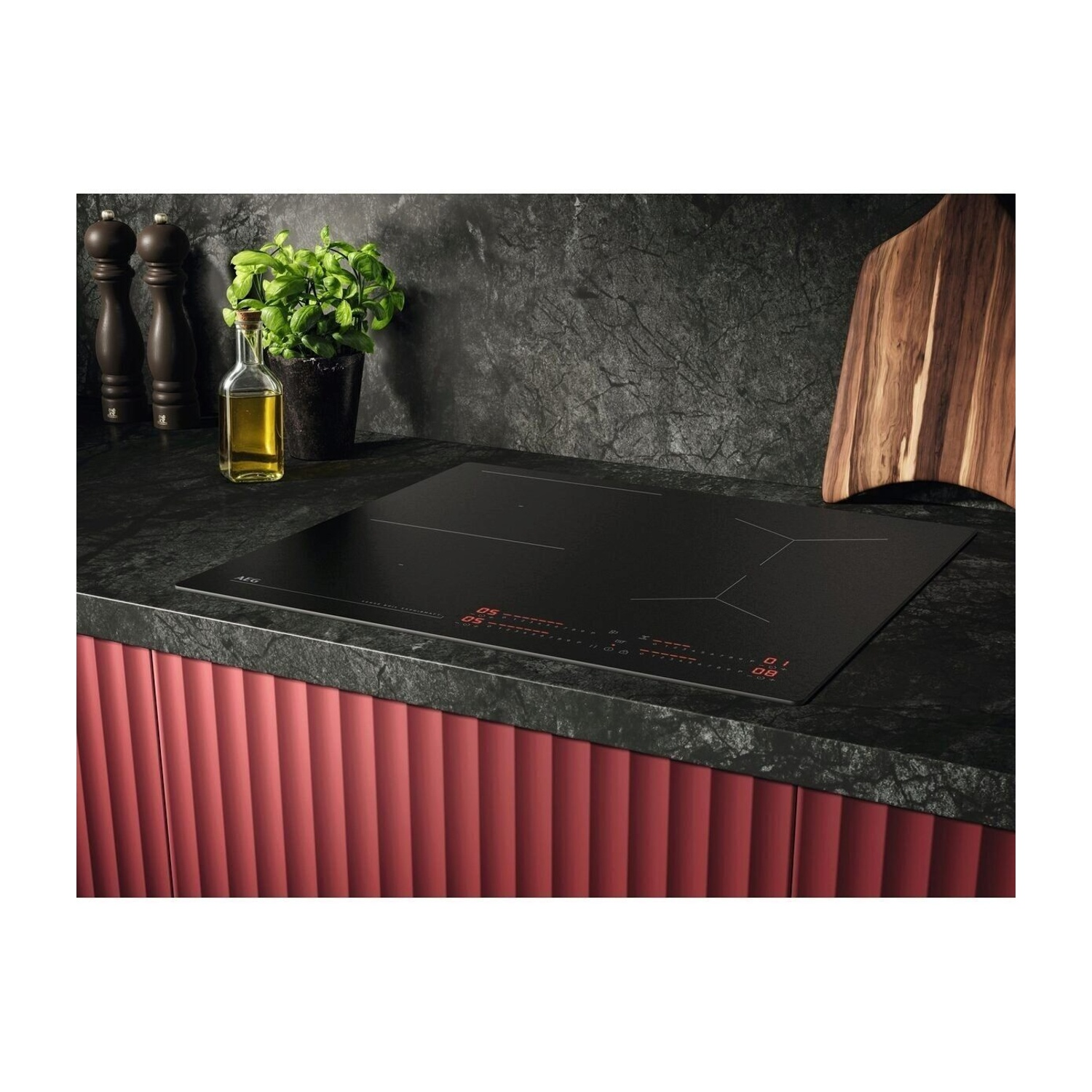 Un piano cottura a induzione nero con controlli rossi e accessori da cucina.