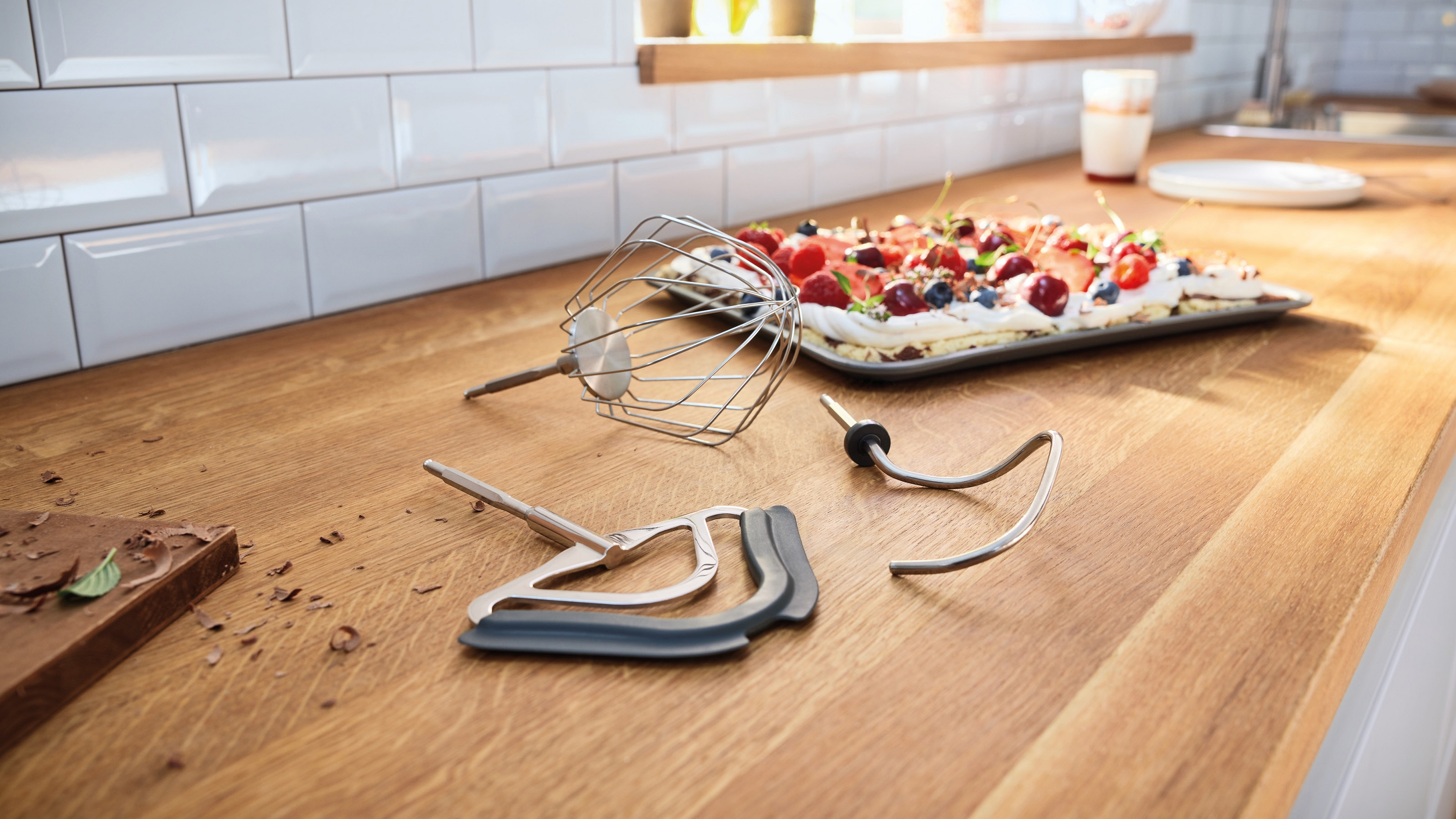 Küchenutensilien und ein Kuchen mit Beeren auf einem Holztresen.