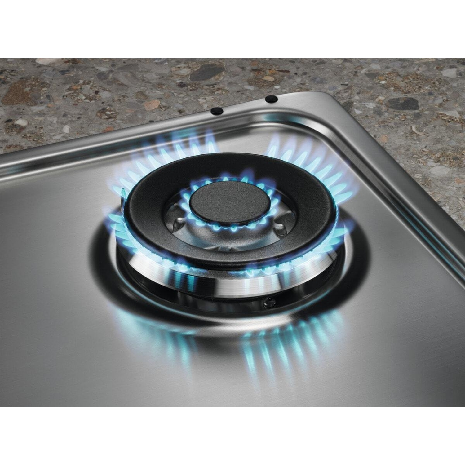 Un bruciatore a gas su un piano cottura in acciaio inox con fiamma blu.