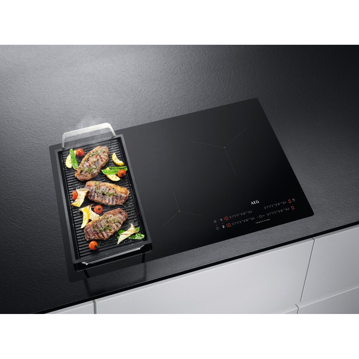 Bistecca e verdure in padella grill su piano cottura a induzione nero con controlli digitali.