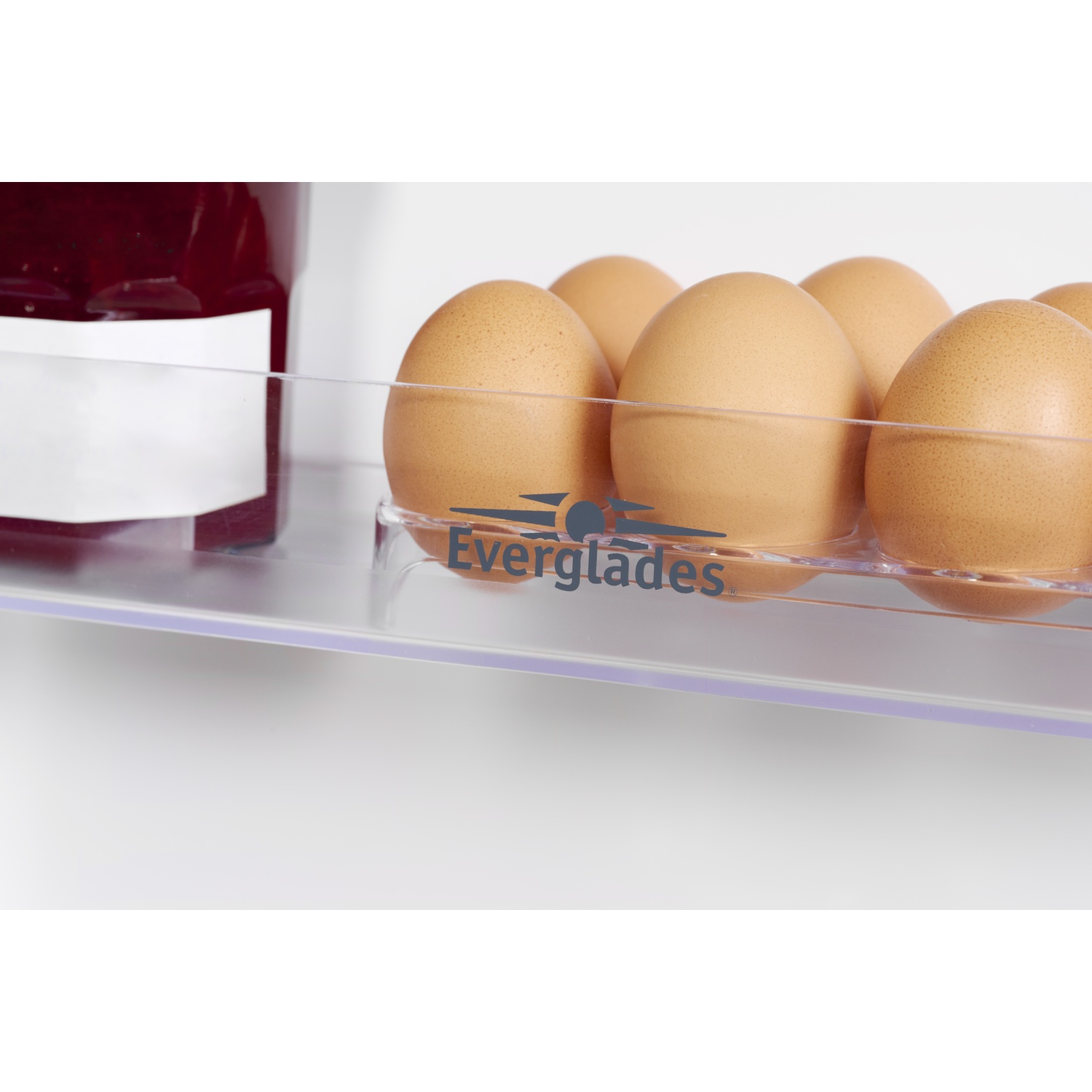 Brown eggs in a clear container with a jar of jam in the background.