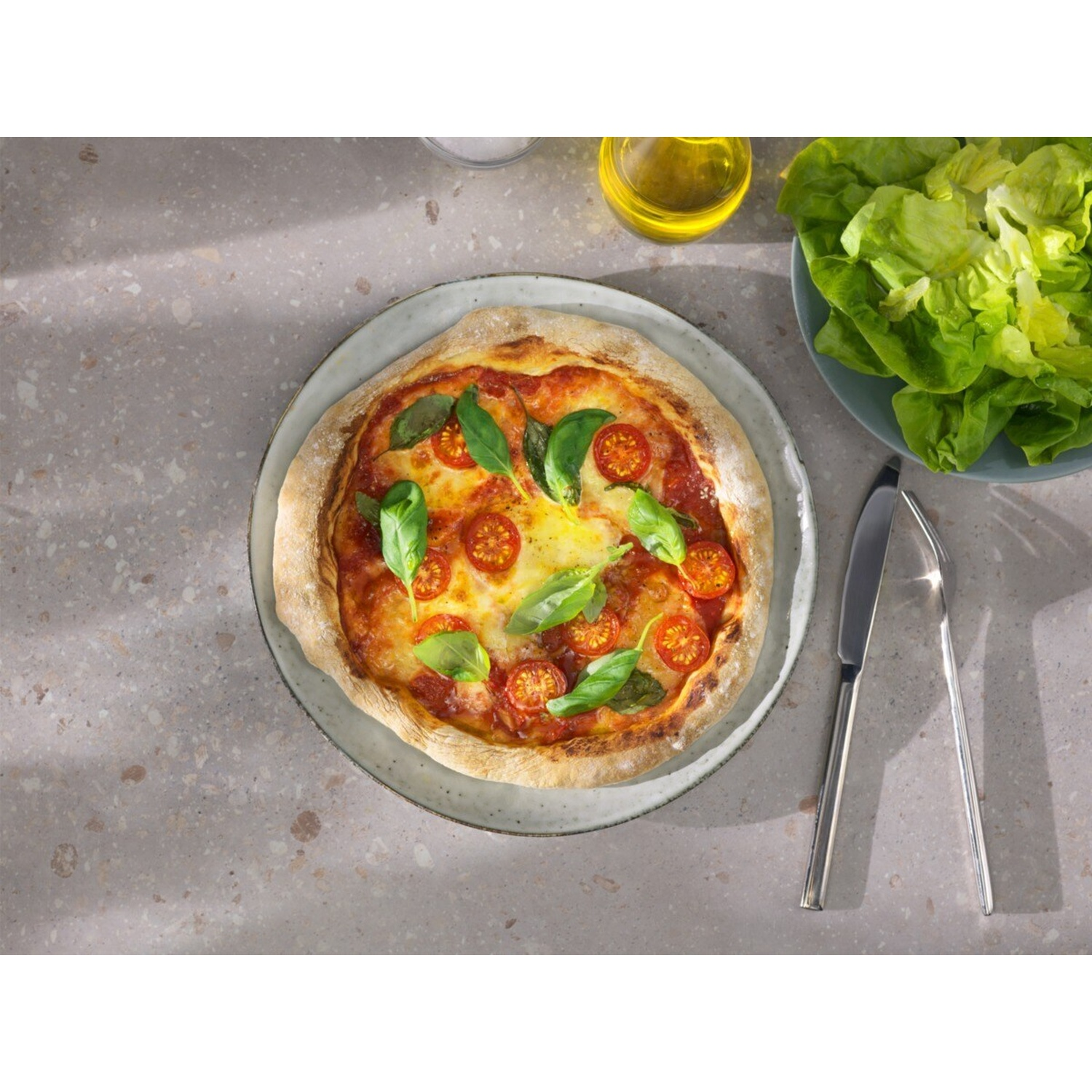 Una pizza Margherita con pomodorini, basilico e insalata.
