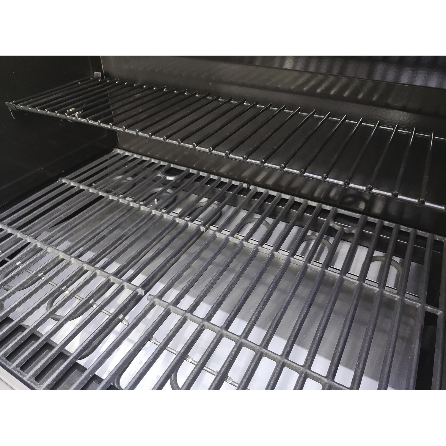 Deux grilles de barbecue empilées dans un barbecue noir, avec des serpentins chauffants en dessous.