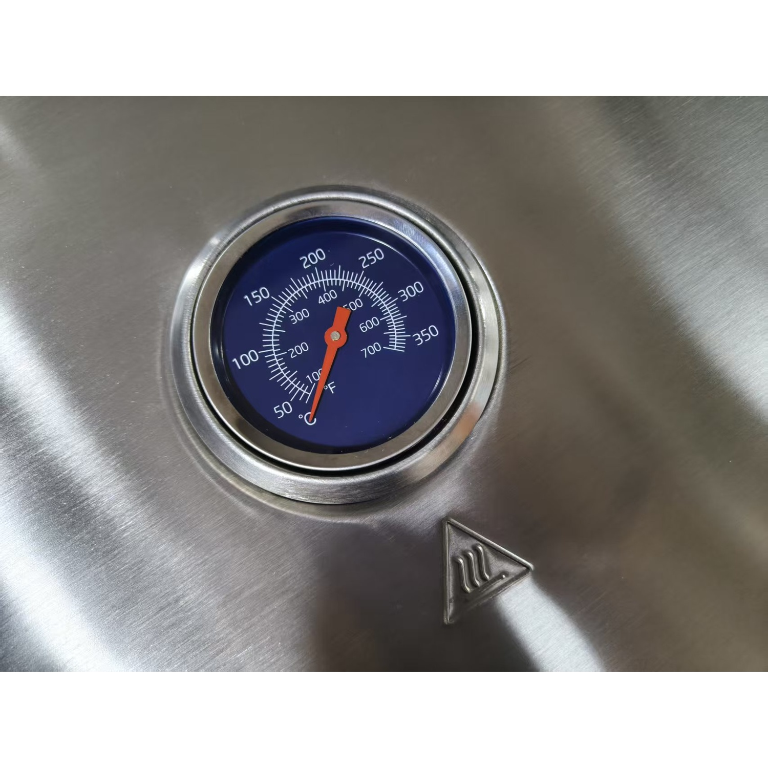 Un thermomètre de grill avec cadran bleu indique 150°F. Un symbole de chaleur est à côté.