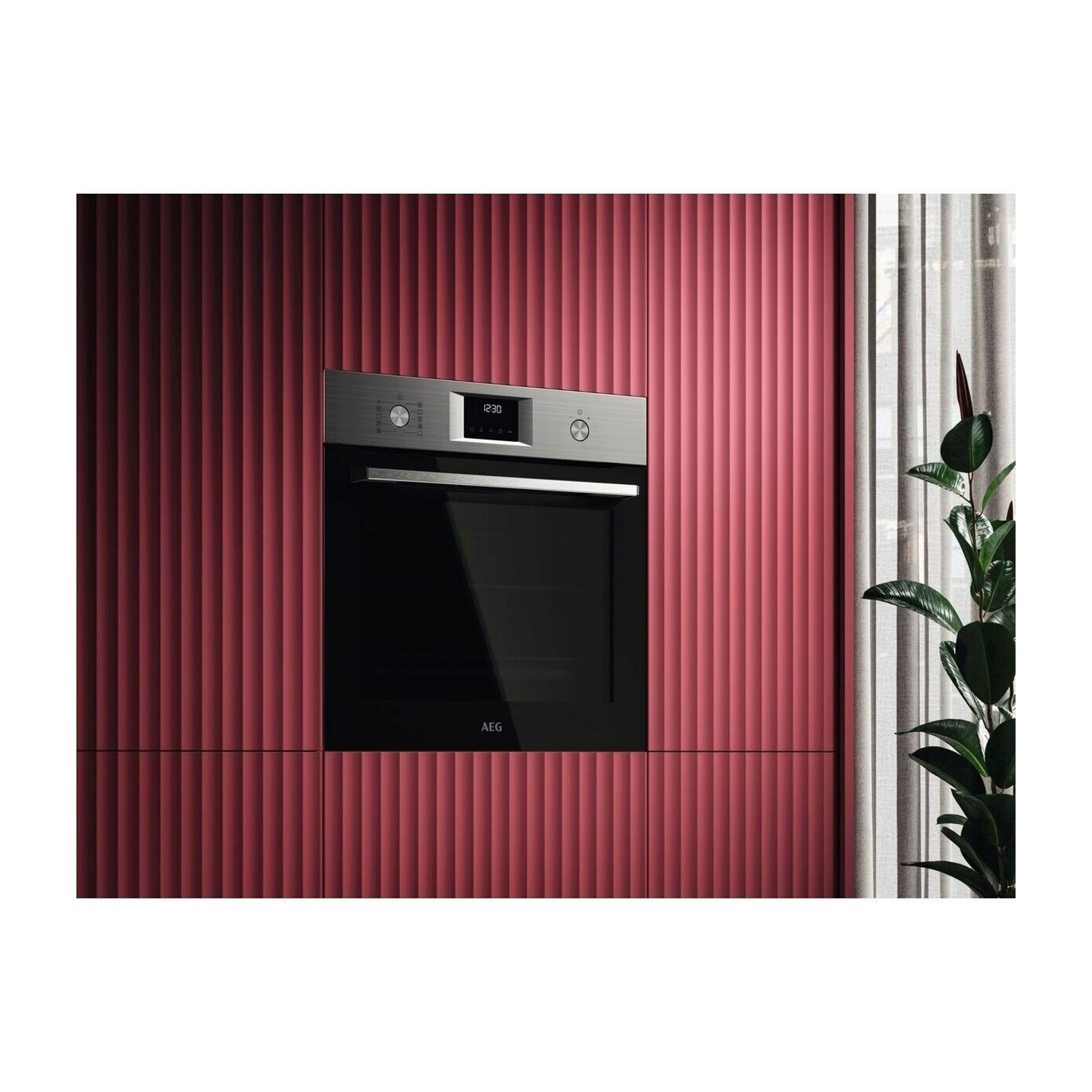 Un forno da incasso moderno con frontale argento e porta nera su sfondo rosso.