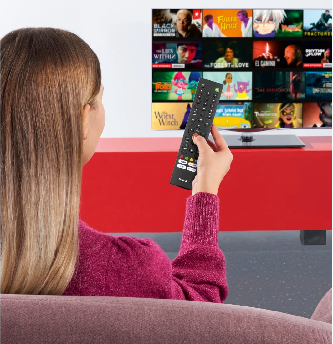 Eine Frau hält eine Fernbedienung und schaut auf einen Fernsehbildschirm mit Filmplakaten.