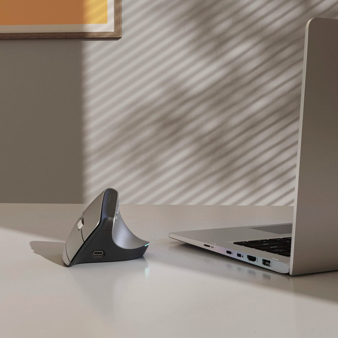 Ergonomikus egér töltő dokkolóval és laptop asztalon.