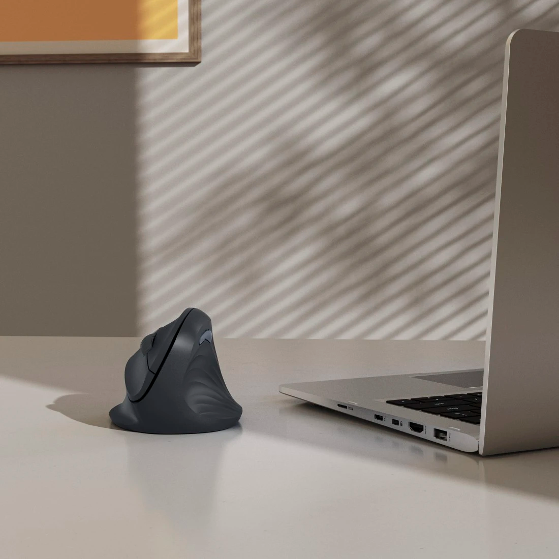 Ergonomikus szürke egér és laptop íróasztalon.