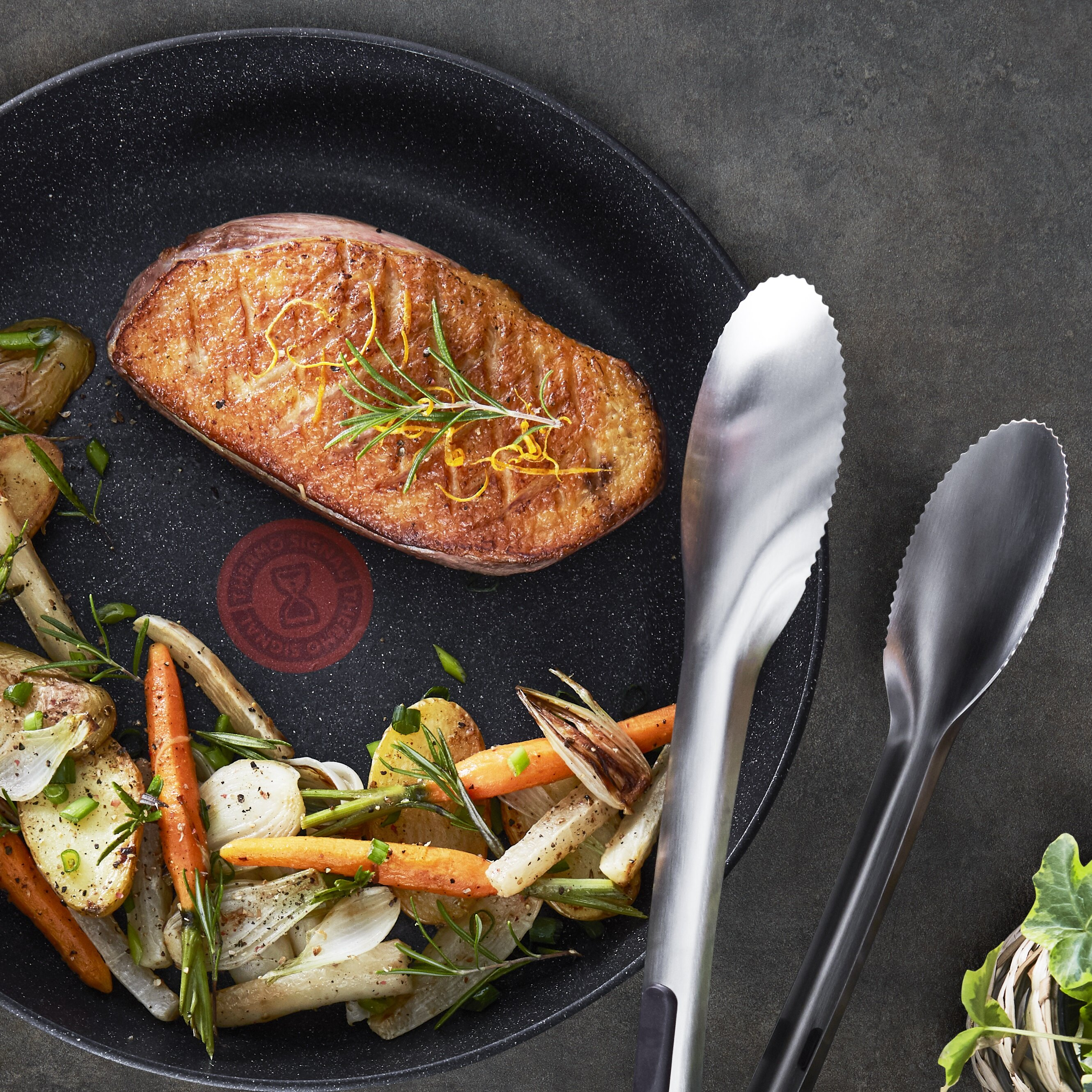 Smażona pierś z kaczki z pieczonymi warzywami korzeniowymi i ziołami na patelni.