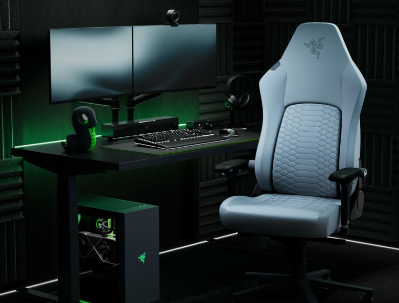 Zestaw do gier z jasnoniebieskim fotelem, biurkiem, dwoma monitorami, komputerem i pluszową wężem.