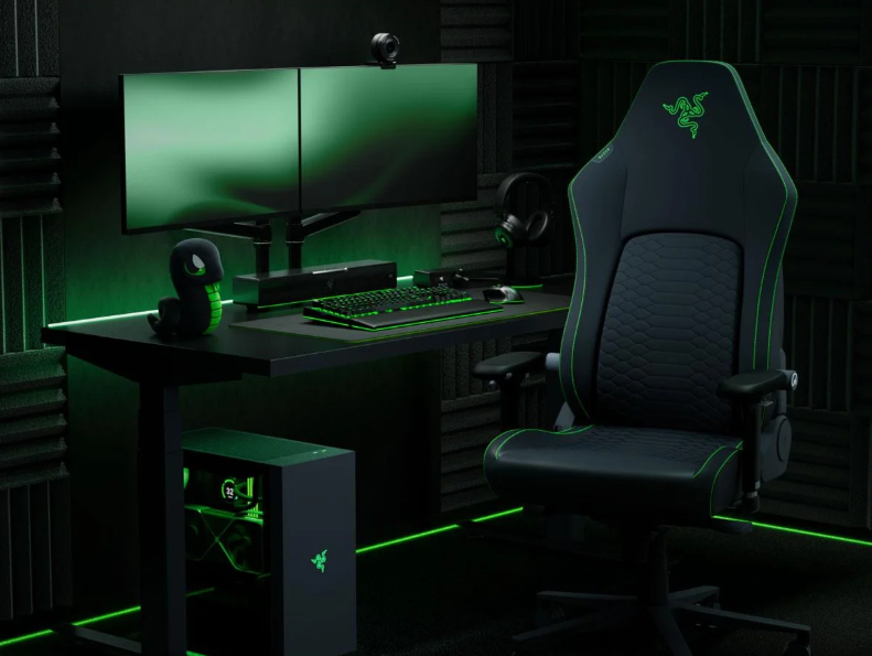 Zestaw do gier z dwoma monitorami, czarnym krzesłem z zielonymi akcentami i PC.
