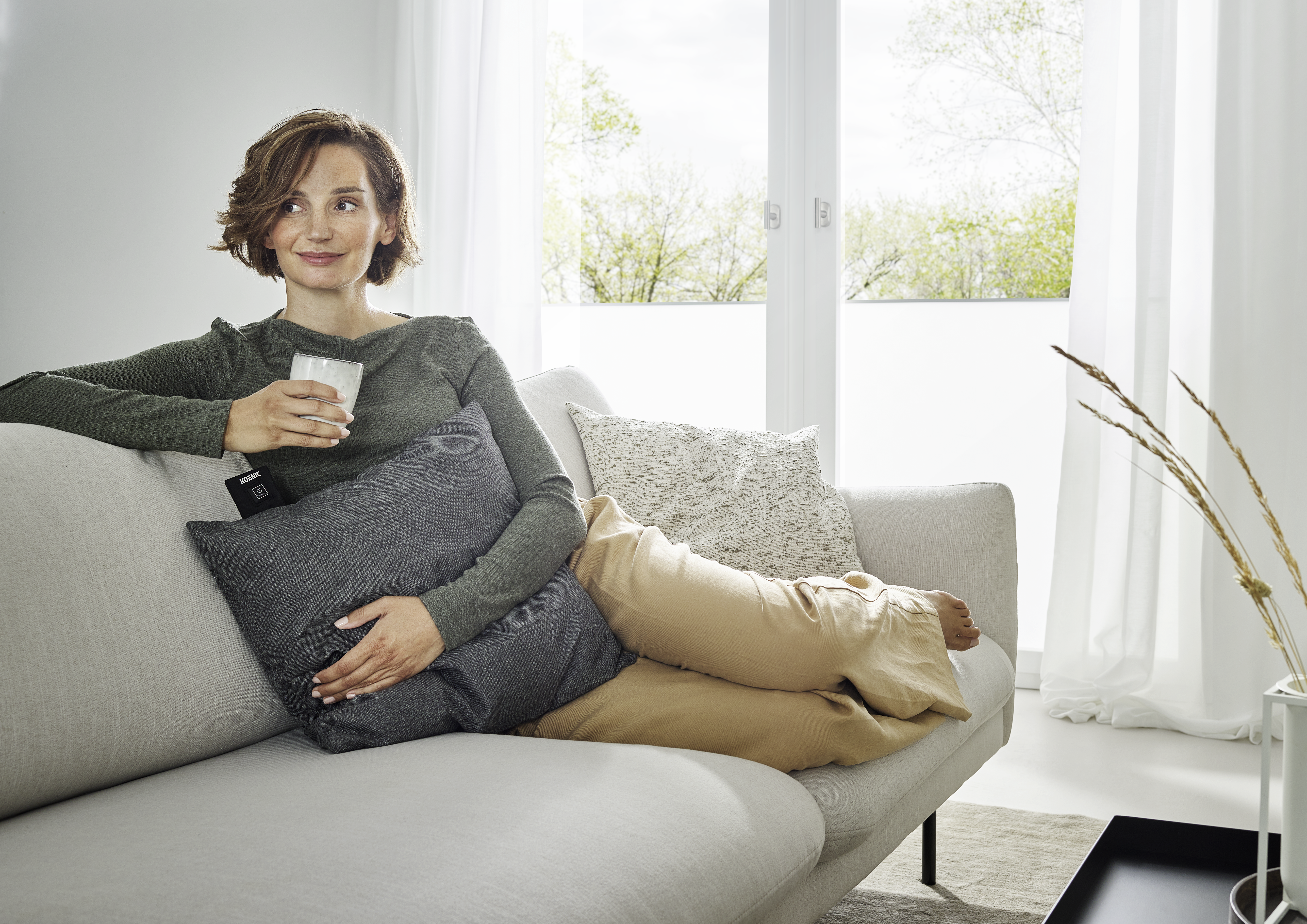 Eine Frau sitzt auf einem Sofa und hält ein Glas.